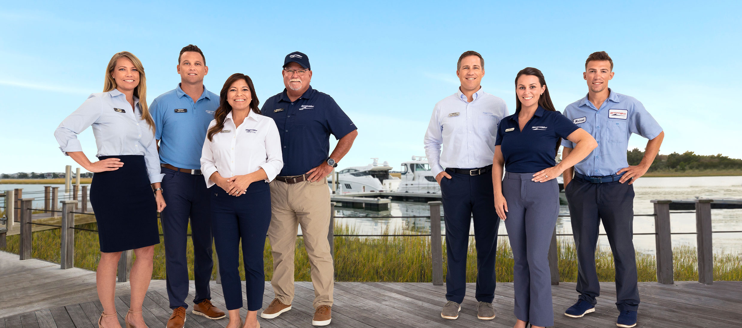 Group of MarineMax employees standing on dock with boats and water behind
