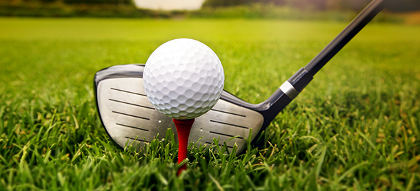 A driver lined up behind a golf ball on a red tee