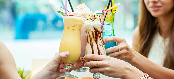 Four tropical beverages are raised together as a toast