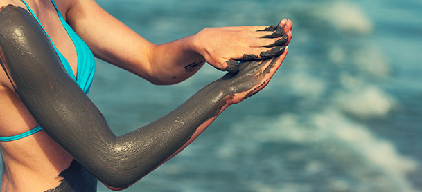 Woman giving herself a mudbath, covering her arm