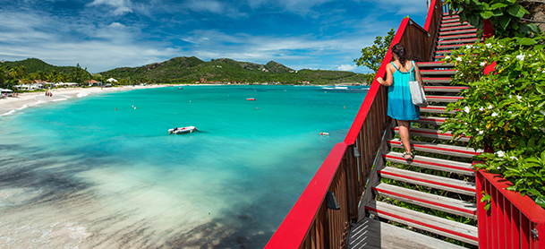 Woman on red staircase overlooking beach and blue water